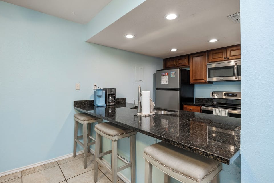 Your fully equipped kitchen features granite countertops, stainless steel appliances, and a breakfast bar for morning coffee.