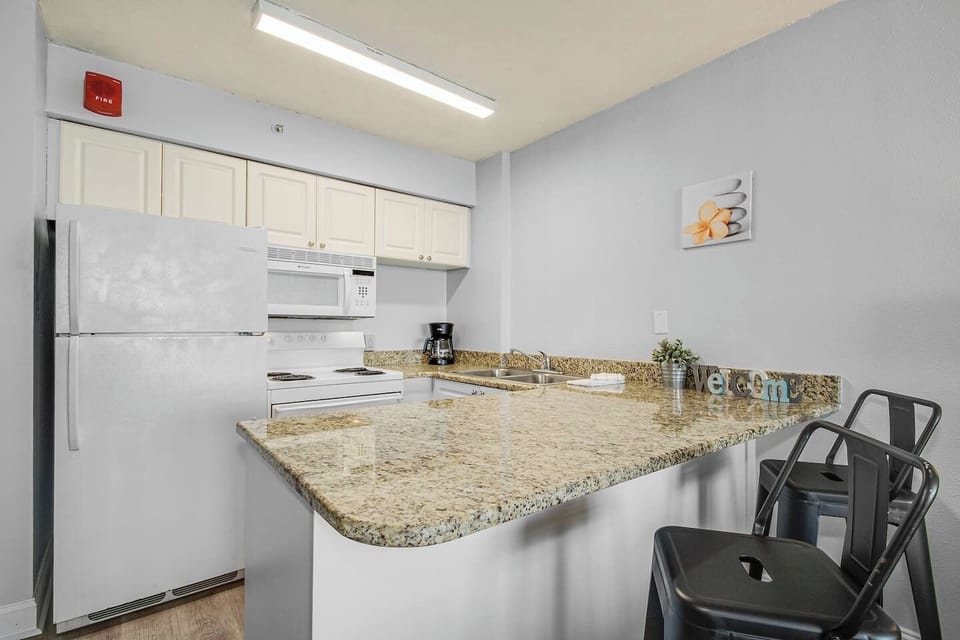 The kitchen area exudes coastal charm, complementing the suite's overall aesthetic for a truly immersive oceanfront living experience.
