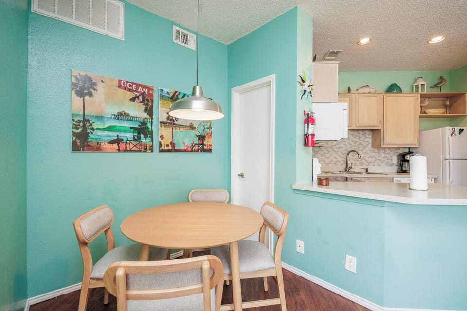 Gather around your bright dining table for coastal-themed meals in this cheerful turquoise space that flows into your fully-equipped kitchen.