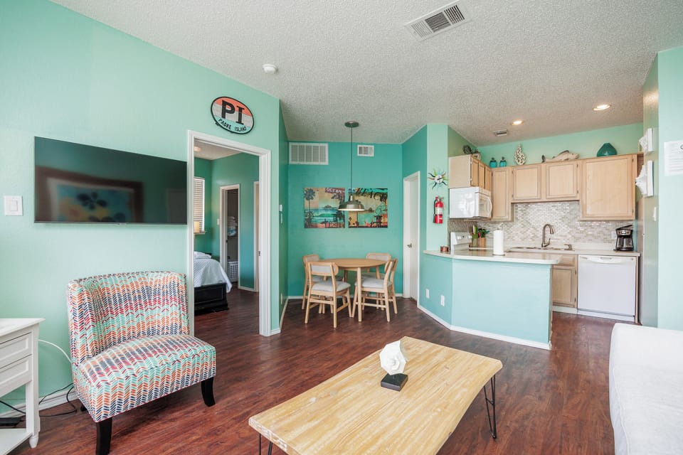 Relax in your cheerful open-plan living space with vibrant turquoise walls, modern kitchen, and coastal charm throughout.