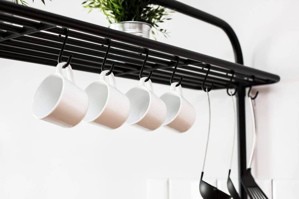 A close-up shot of a black metal rack hanging from the ceiling, holding white coffee mugs, adding a modern touch to the kitchen space.
