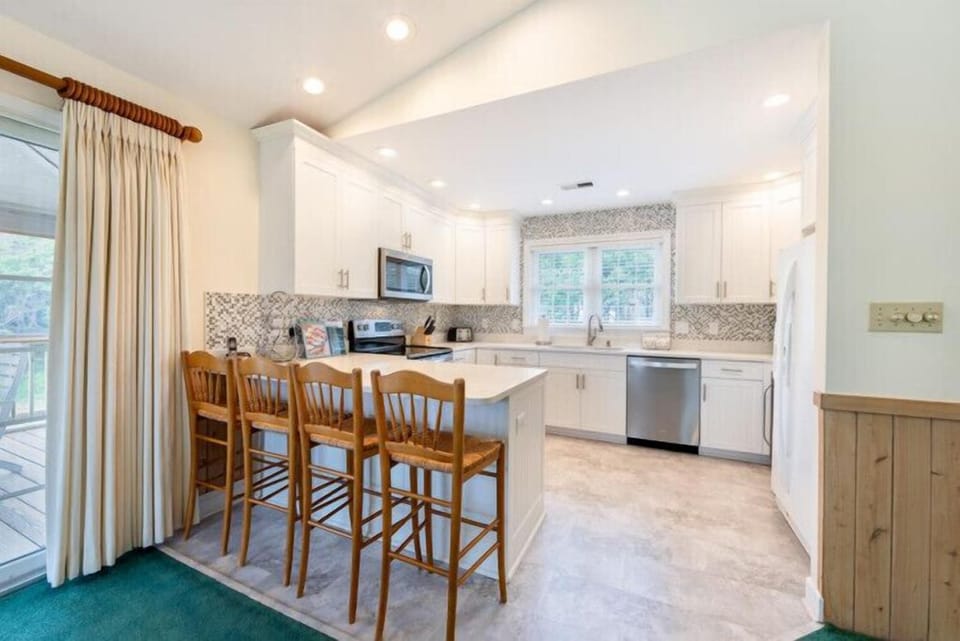 Your fully equipped kitchen features modern stainless appliances, elegant cabinetry, and a welcoming island with seating—perfect for cooking meals together or enjoying morning coffee in the bright, inviting space.