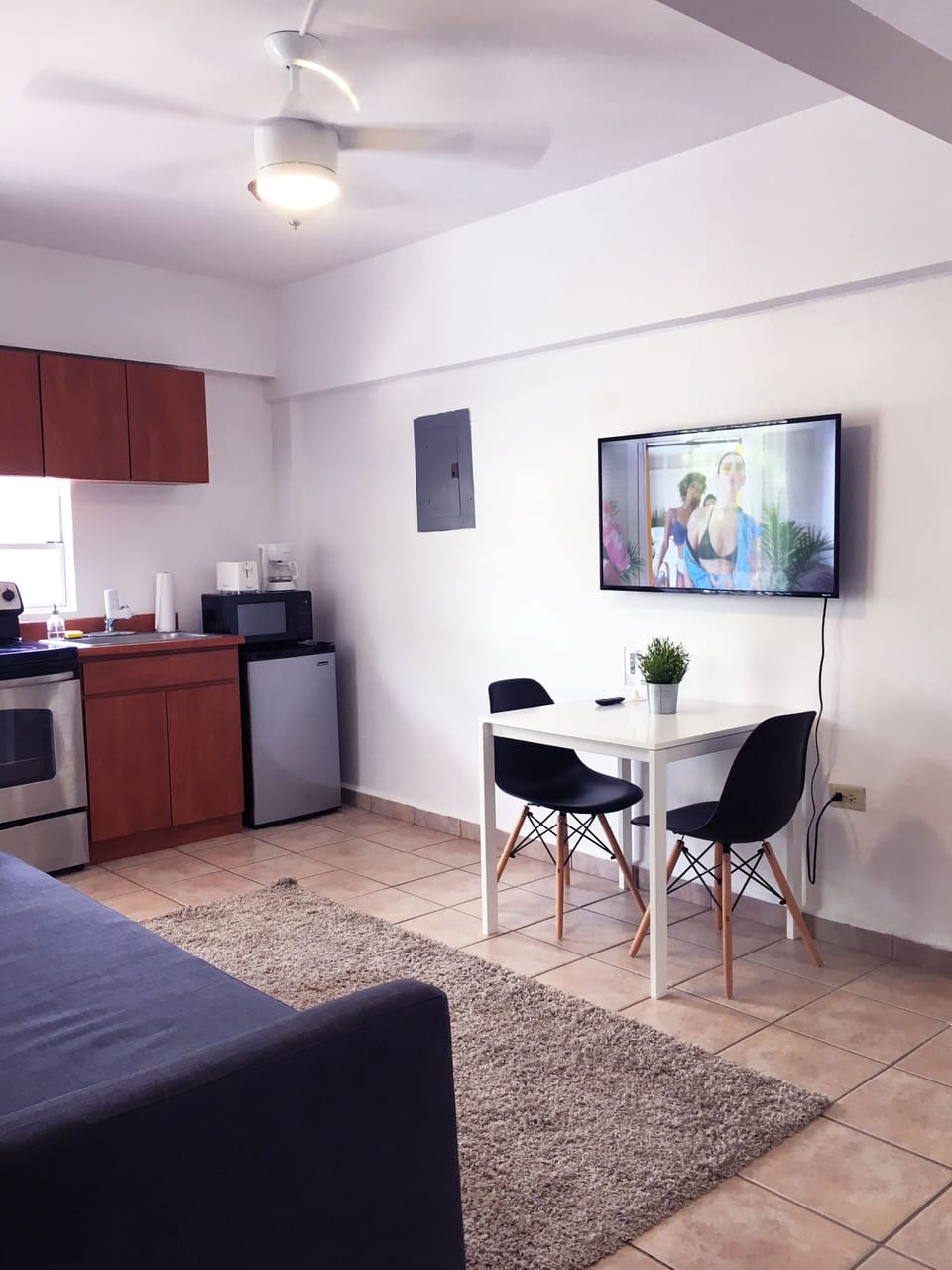 Area de comedor con 2 sillas, smart TV y esta proximo al area de cocina.