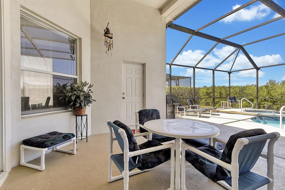 Covered patio with ceiling fan, table and lounge chairs.