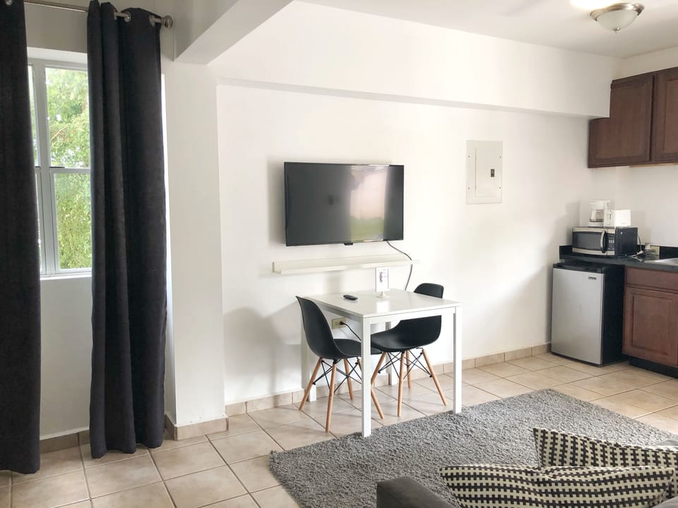 Area de comedor con 2 sillas, smart TV y esta proximo al area de cocina.