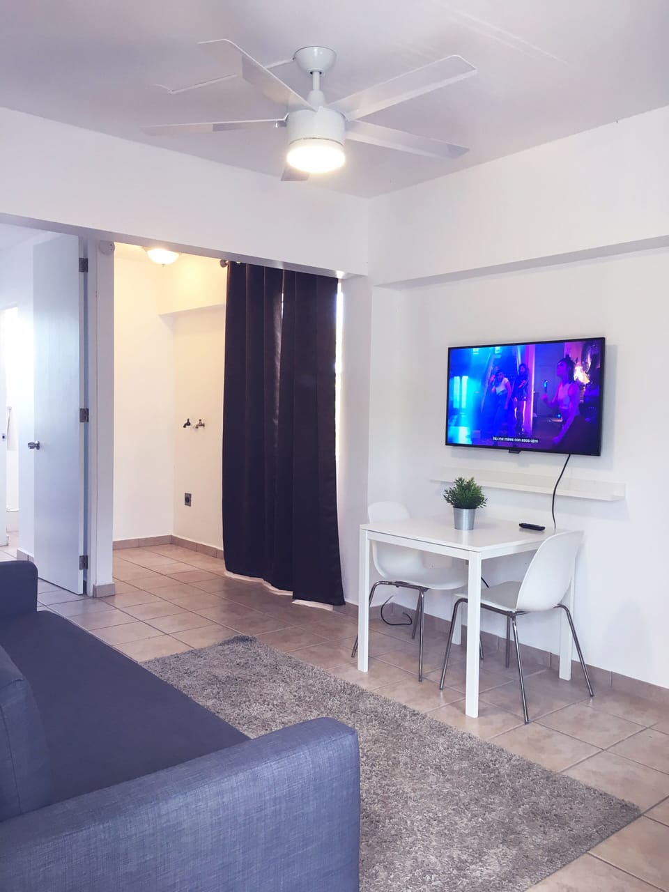 Area de comedor con 2 sillas, smart TV y esta proximo al area de cocina.
