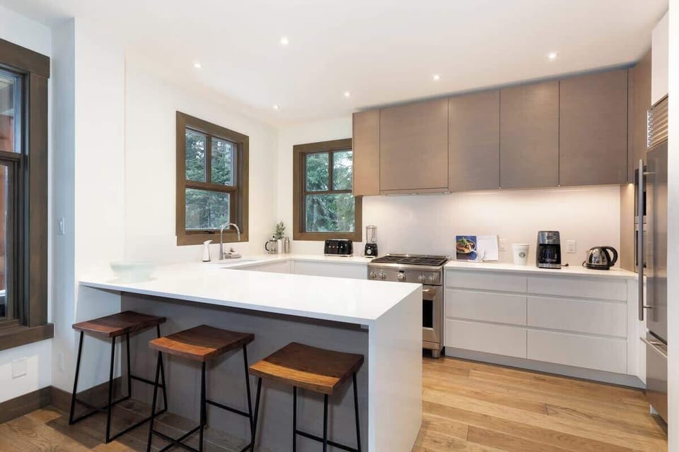 - Modern kitchen with sleek design and wood accents  
- Fully equipped gourmet kitchen for mountain dining experience  
- Bright open layout with forest views and natural light  