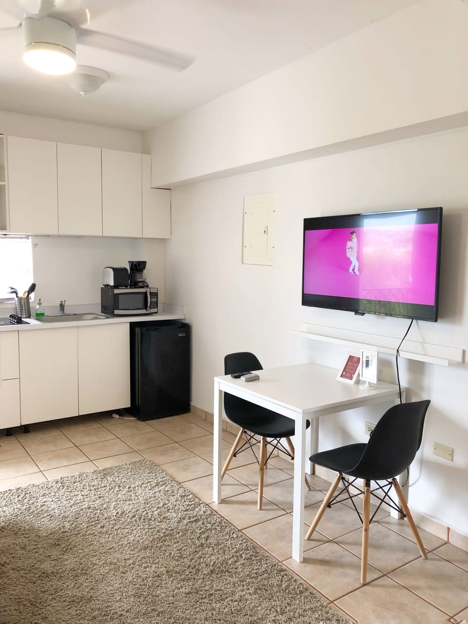 Area de comedor con 2 sillas, smart TV y esta proximo al area de cocina.