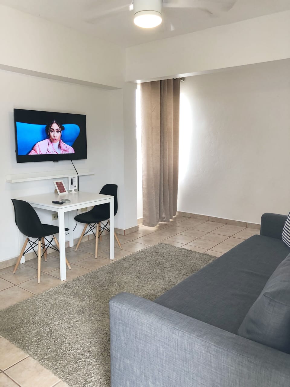 Area de comedor con 2 sillas, smart TV y esta proximo al area de cocina.