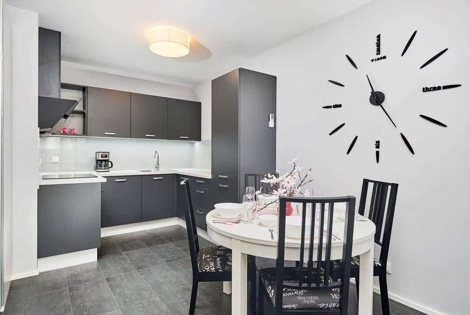 Kitchen of Świstackiego 19/10 with dining area, stove, oven, fridge, dishwasher, kettle, coffee machine, toaster and cupboards