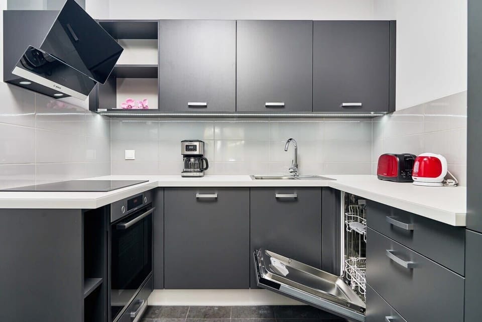 Kitchen of Świstackiego 19/10 with dining area, stove, oven, fridge, dishwasher, kettle, coffee machine, toaster and cupboards