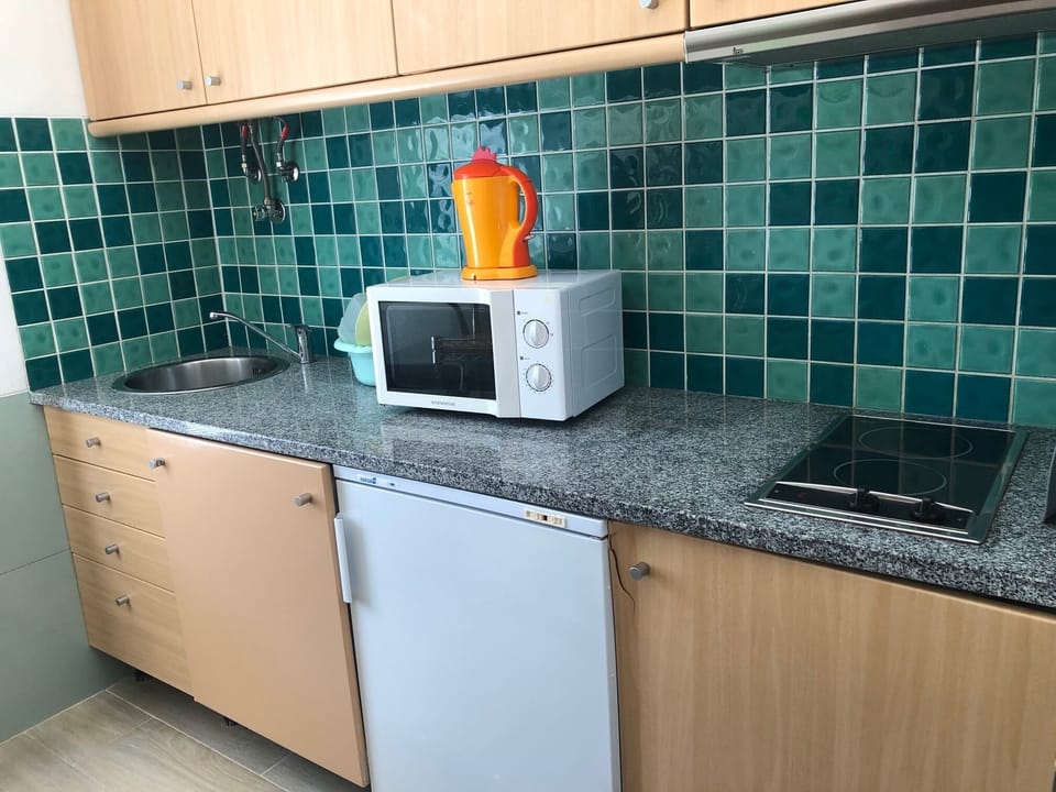 Cozinha com microondas, frigorífico, máquina da loiça e placa cerâmica