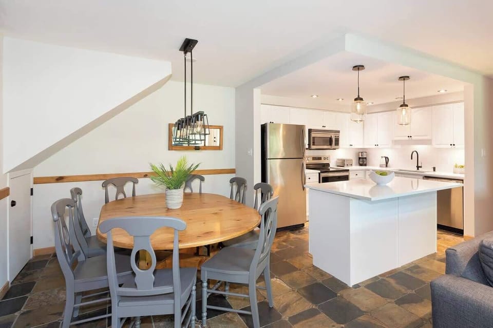 - Dining area with wooden table and modern hanging lights  
- Open layout connects easily with the bright white kitchen  
- Perfect spot to share meals after skiing or exploring trails  
