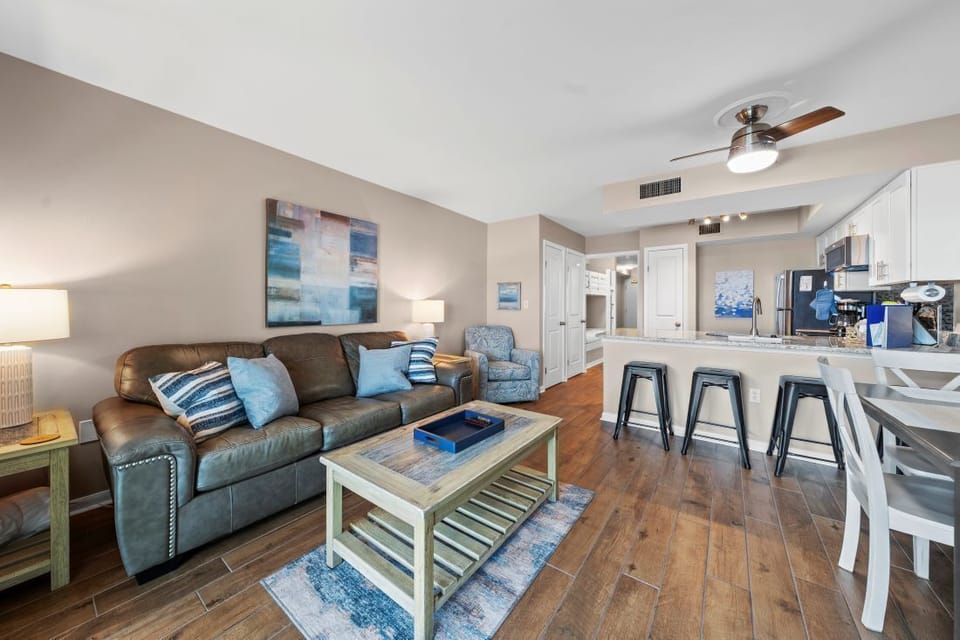Relax in your spacious open-plan living area with coastal-inspired decor, comfortable leather seating, and modern kitchen perfect for vacation dining.