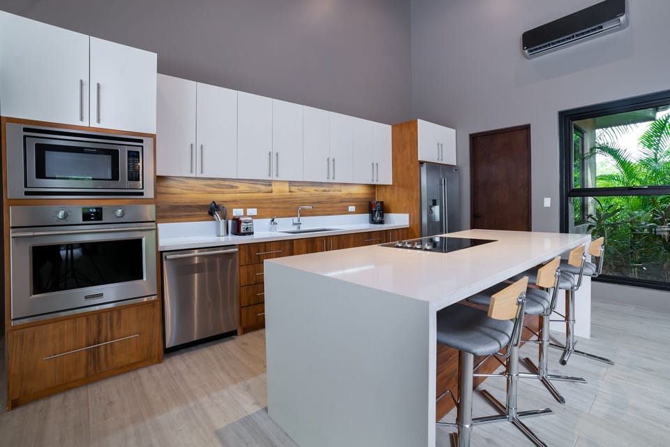 Step into the bright kitchen a space that embodies modern elegance with its clean white decor and contemporary furniture.