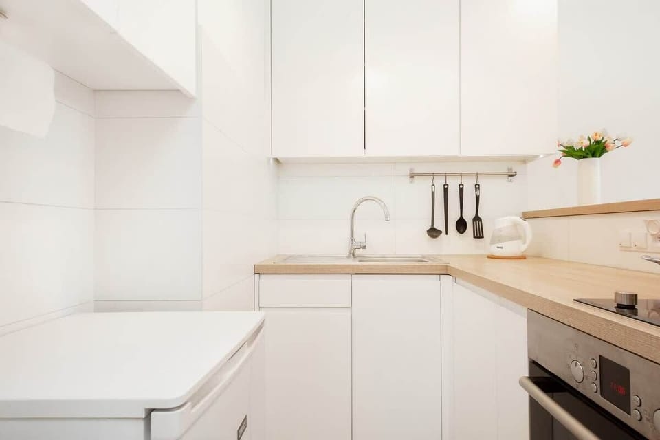 A modern, compact kitchen with white cabinets, stainless steel appliances, and efficient layout for easy meal prep.