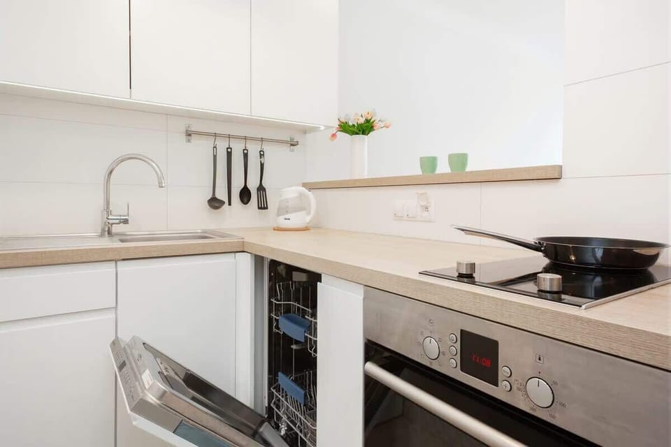 Another angle of the kitchen showing countertop space, storage, and minimalist white cabinetry.