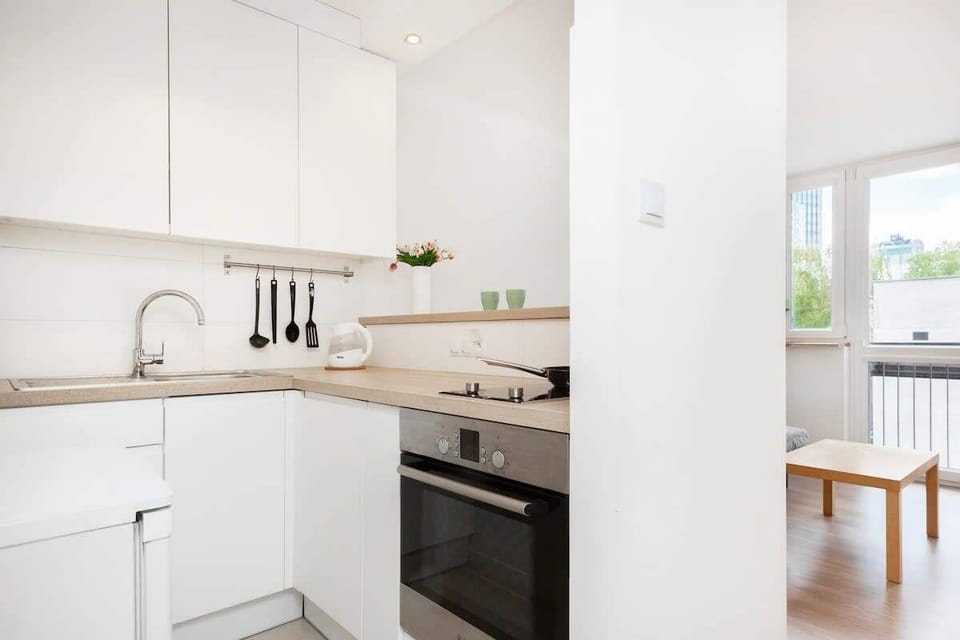 Another angle of the kitchen showing countertop space, storage, and minimalist white cabinetry.