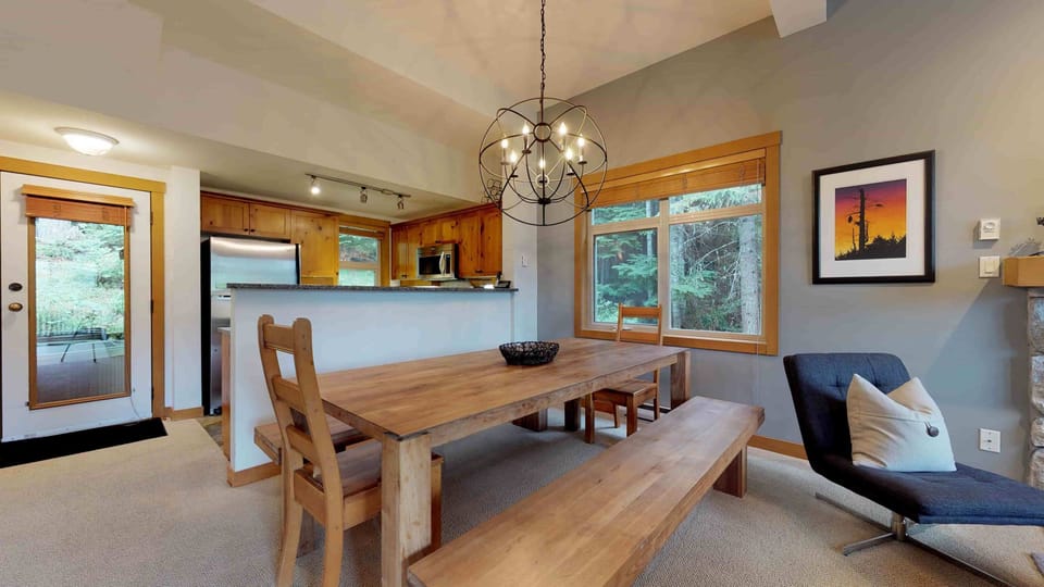 - Dining area with modern chandelier and forest-view windows  