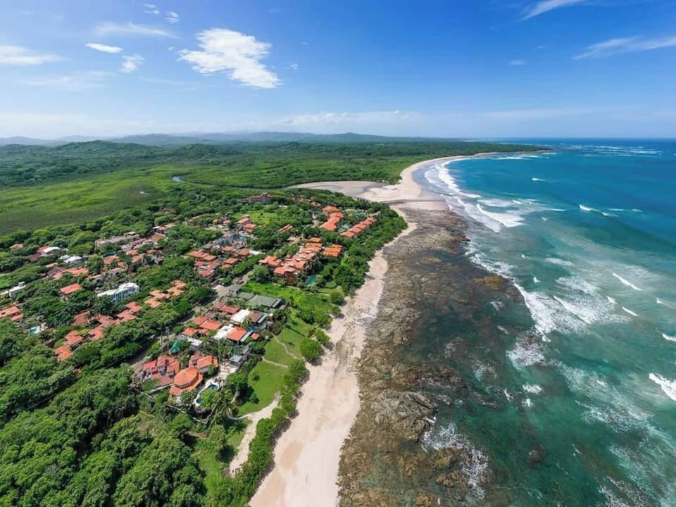 Aerial view of Langosta Beach in Tamarindo, showcasing its pristine sandy shores, gentle waves, and perfect setting for surfing, swimming, and tropical relaxation.