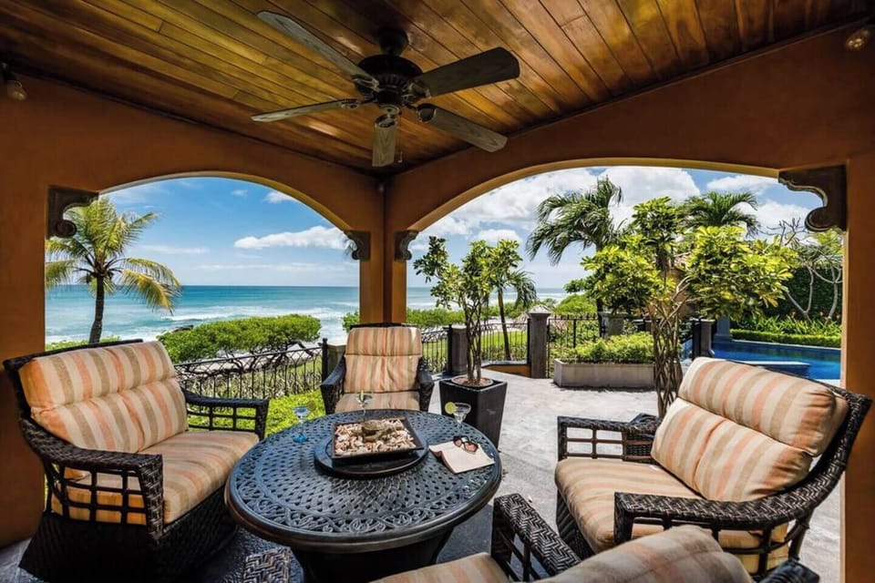 Ocean-view patio at Playa Langosta villa, perfect for enjoying sunset cocktails in comfortable, covered seating while taking in the tropical beach scenery.