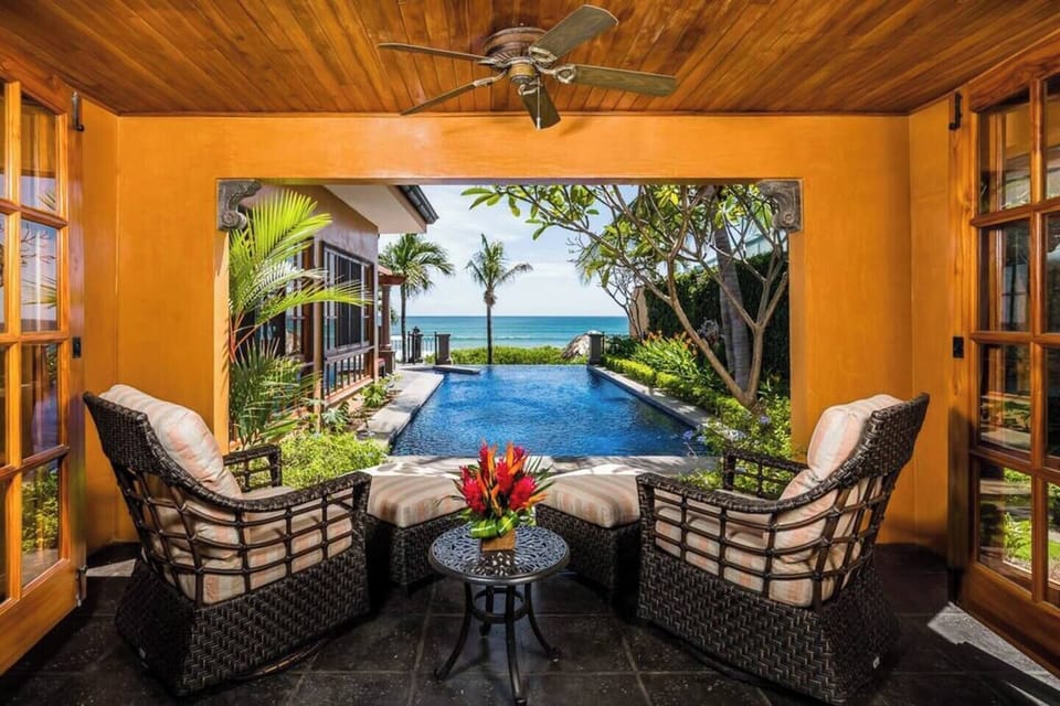 Relax in the master bedroom of this Tamarindo beachfront villa, featuring a cozy seating area with stunning views of the infinity-edge pool flowing into the Pacific Ocean—perfect for enjoying tropical sunsets from the comfort of your villa.