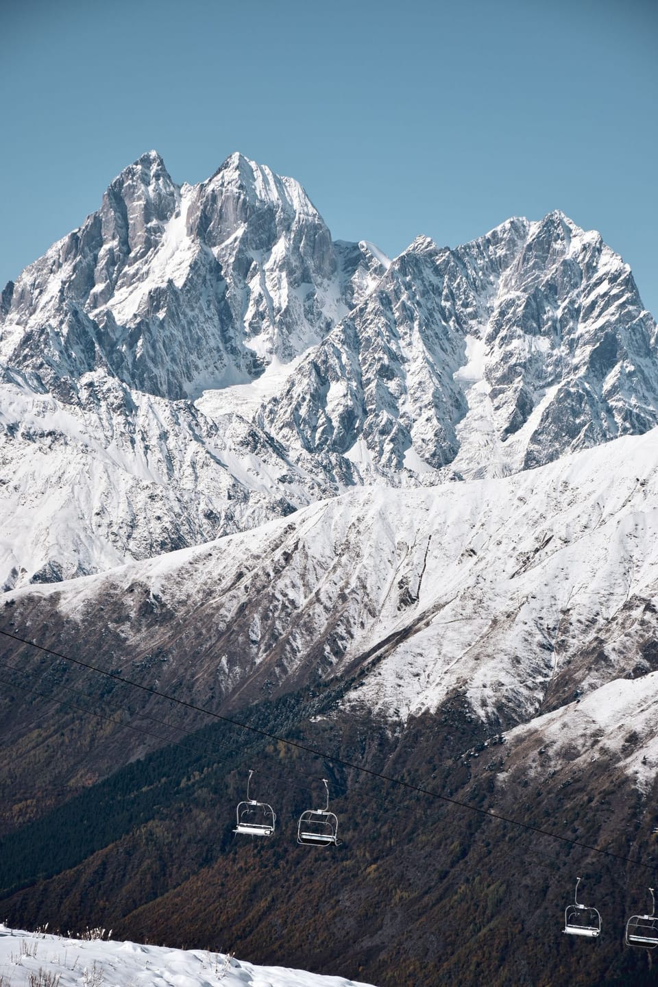 Riding the chairlift beneath the jagged, snow-draped summits towering over the Vars ski domain in the French Alps.