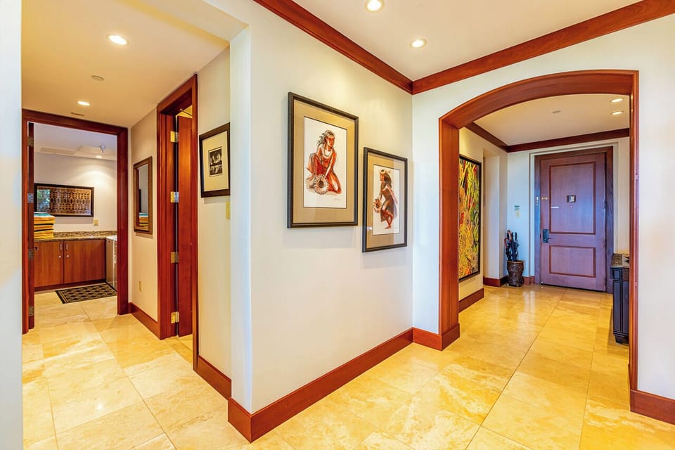 Step into your private sanctuary through gleaming travertine floors and rich mahogany archways. Thoughtfully curated island-inspired artwork and warm wood accents set the tone for a tropical escape that feels both elegant and welcoming.