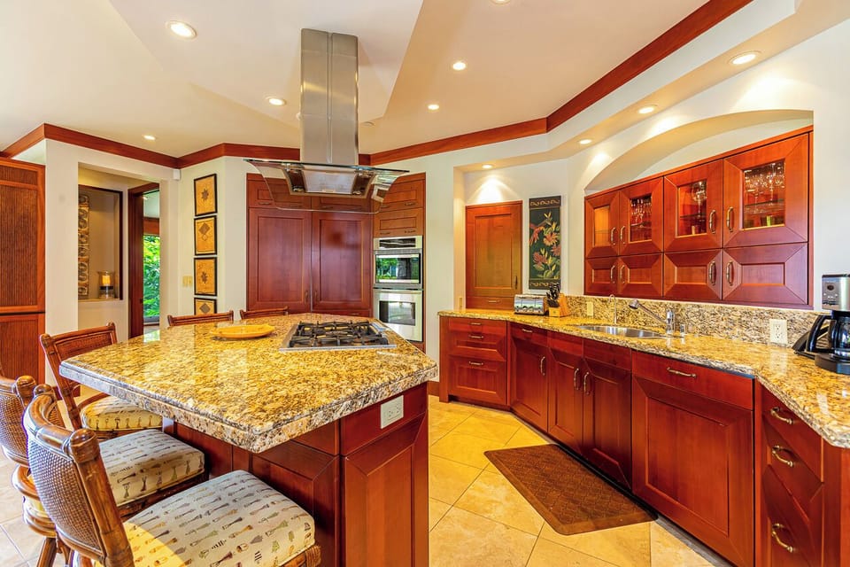Prepare your favorite meals in this beautiful gourmet kitchen, featuring rich wood cabinetry, gleaming granite countertops, professional-grade appliances, and a spacious island perfect for both cooking and gathering.