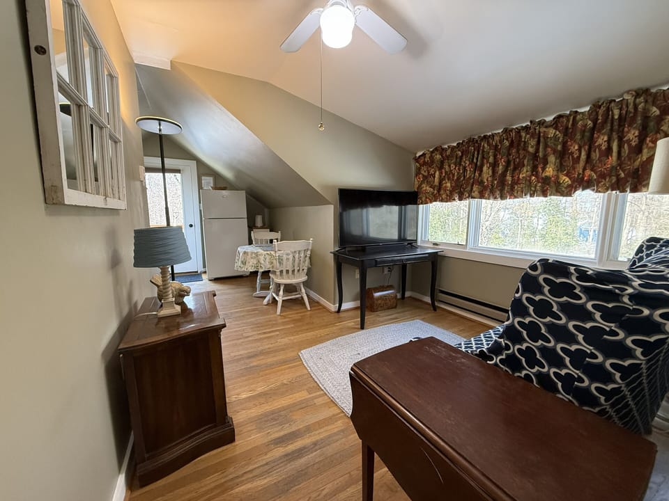 Sitting room area.TV and Work Desk In the Background. Large Window for Light.


