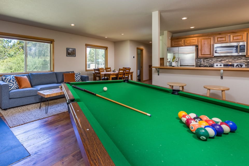 Open concept ground floor kitchen, bar, dining area, & living area w/ pool table