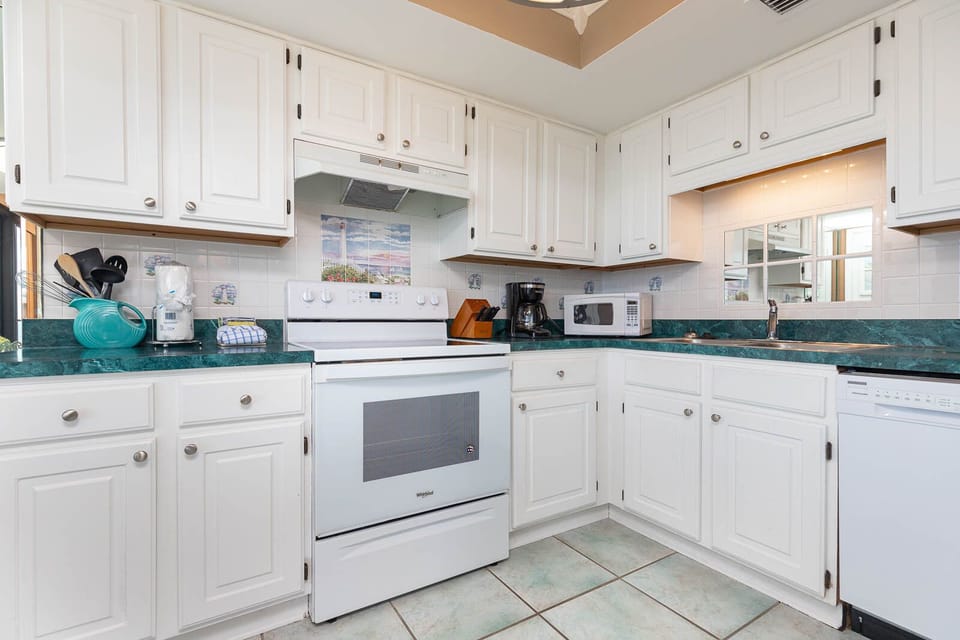 Inviting kitchen featuring white cabinetry and appliances, a vibrant turquoise countertop, and coffee maker