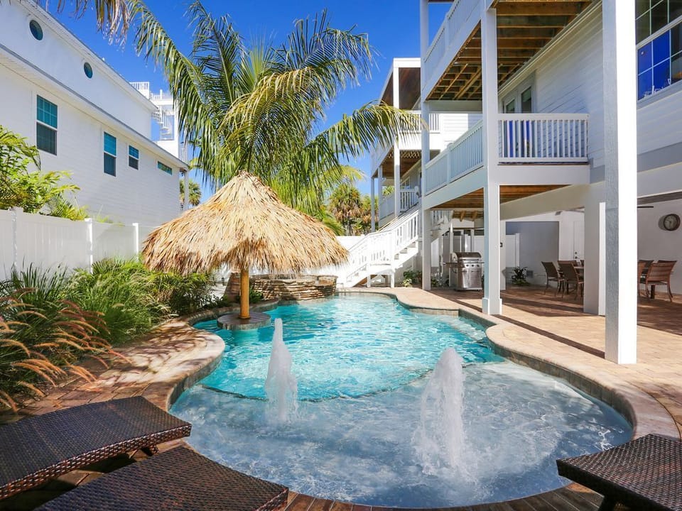 Large heated pool has a tanning deck, a swim up bar and spa. Water spraying up is AI to the picture.