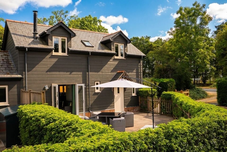 Charming Hayloft exterior with a sunny patio nestled against woodland.