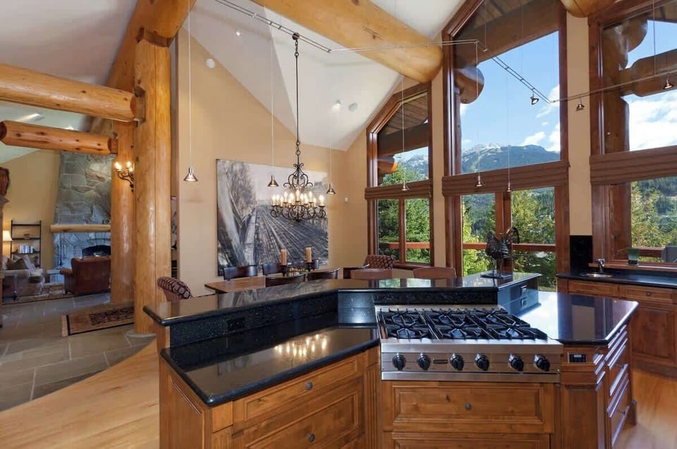 - Modern chef’s kitchen with double ovens, gas range, and wide mountain-view windows  
- Bright open-concept design connects seamlessly to the elegant dining and lounge area  
- Cook while enjoying Whistler’s scenic beauty through tall glass
