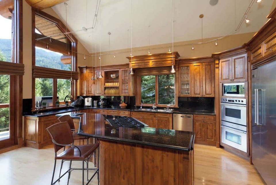 - Gourmet kitchen with granite countertops, high-end appliances, and panoramic views  
- Open layout connects to dining and living areas, ideal for group cooking sessions  
- Surrounded by nature and wood textures for an authentic mountain-lodge