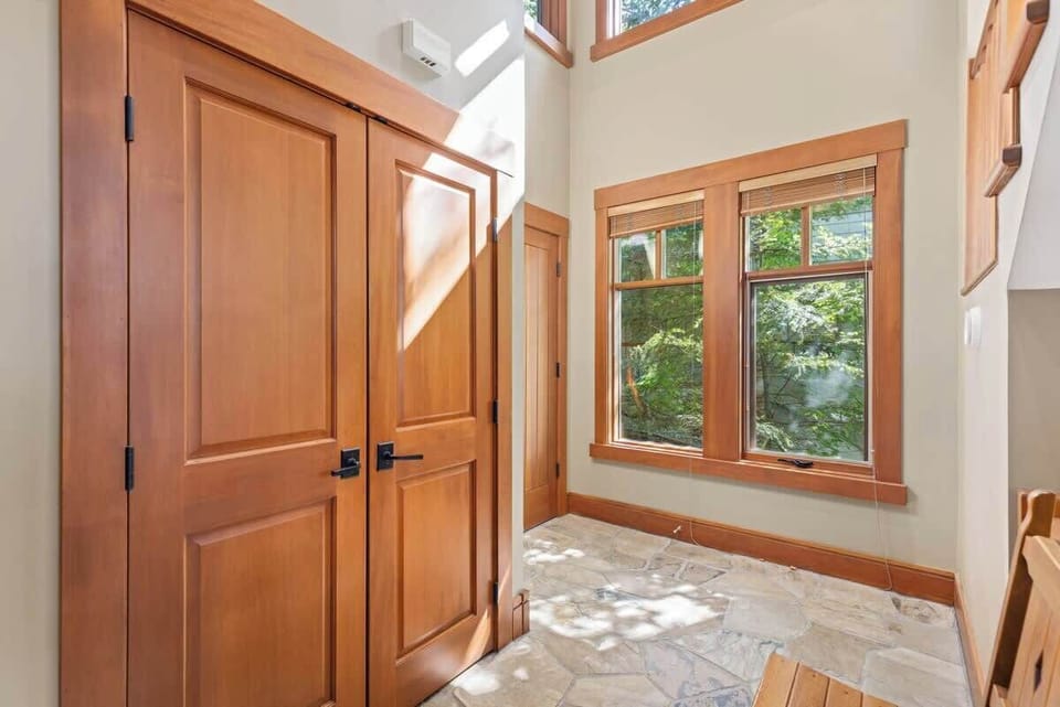 - Sunlit hallway with wooden finishes and stone flooring  
- Large windows showcase forest views and natural warmth  
- Inviting space that enhances the cabin’s rustic charm  
