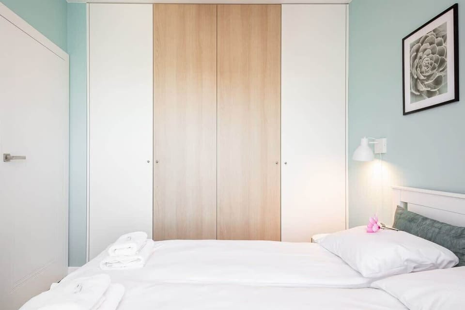A peaceful bedroom with light blue walls, a comfortable bed, and soft lighting. Decorative wall art and bedside tables complete the inviting look.