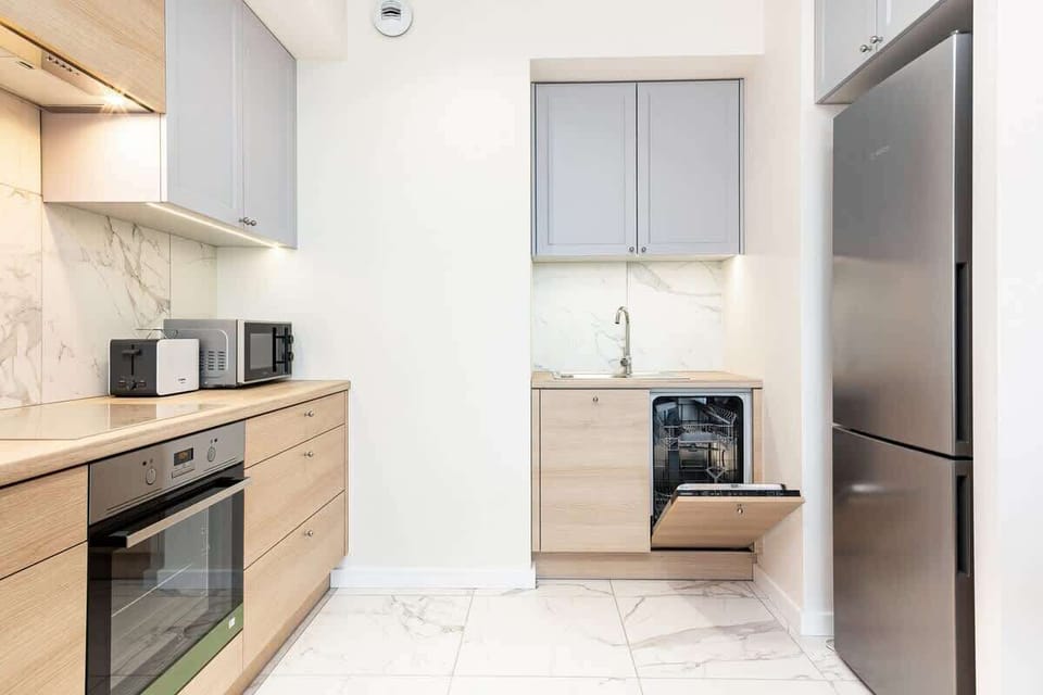 A compact, modern kitchen with light wooden cabinetry and integrated appliances. The design is functional and clean.
