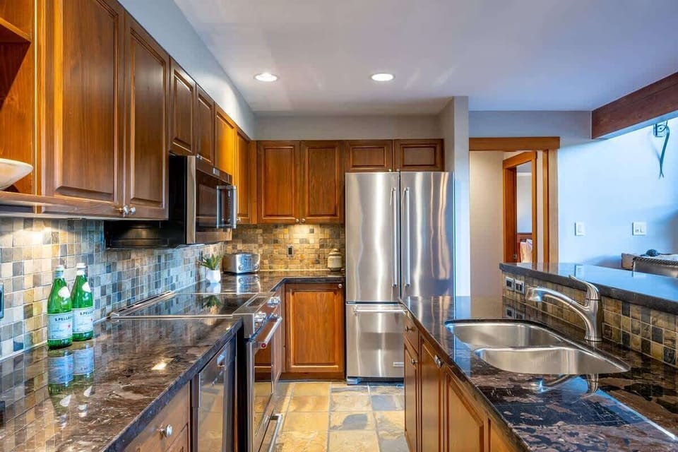 - Sleek kitchen with granite countertops and stainless steel fridge  
- Warm wood cabinetry adds cozy alpine style to your cooking space  
- Fully equipped setup for effortless vacation meal prep  