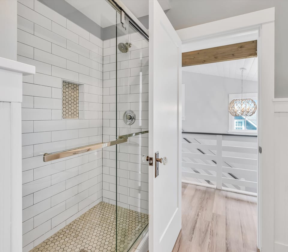Step into your private sanctuary with a bright, modern shower featuring clean subway tiles and a soothing rainfall head. Your bedroom awaits just beyond the door.