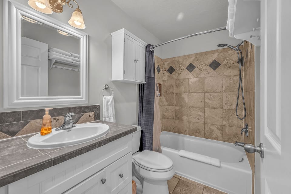 Unwind in your elegantly appointed bathroom featuring marble countertops, designer tilework, and a relaxing tub-shower combination for your comfort.
