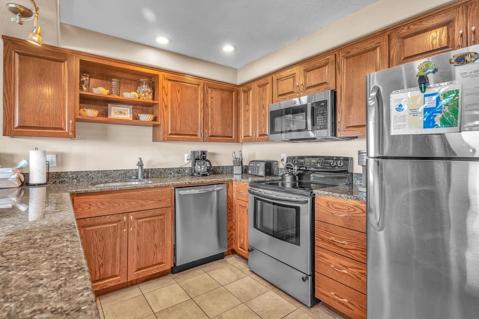 Your fully equipped kitchen features granite counters, stainless appliances, and rich wood cabinetry perfect for preparing home-cooked meals.