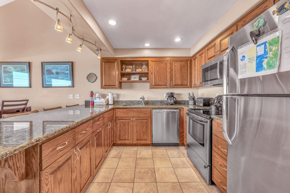 Your fully equipped kitchen features granite countertops, stainless steel appliances, and warm wood cabinetry for preparing memorable meals together.