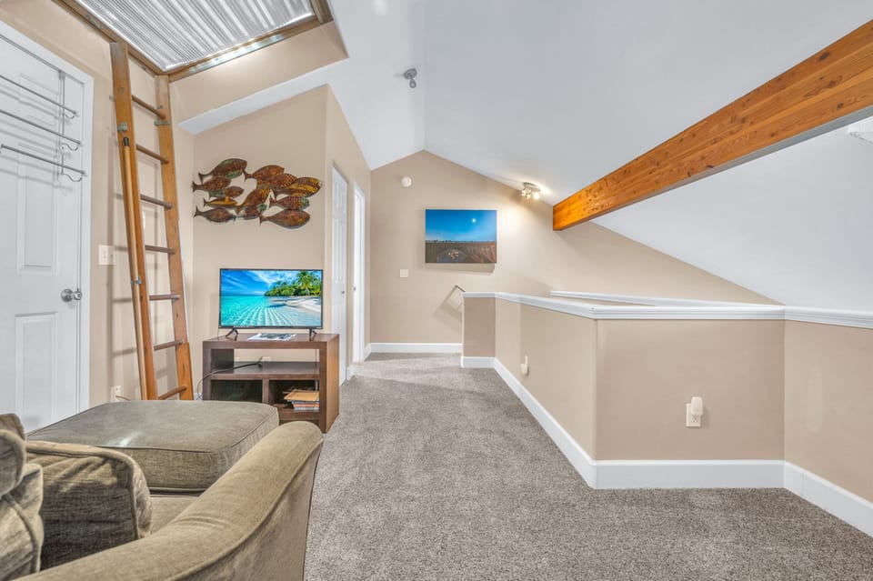 Your own cozy loft retreat with exposed beams, skylight, and entertainment setup for perfect relaxation.