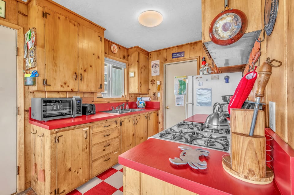 Step into your charming rustic kitchen with warm pine cabinets, bright red counters, and everything you need to create memorable meals together.