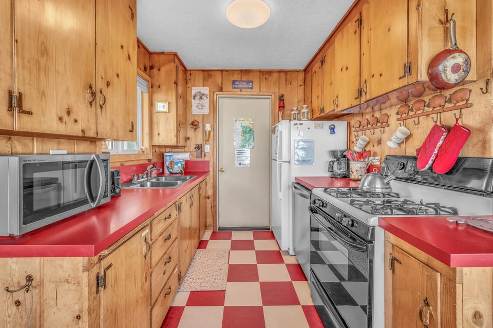 Your fully equipped kitchen welcomes you with warm knotty pine cabinets, bright red countertops, and everything needed to create memorable meals.