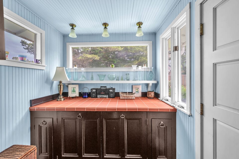 Your charming kitchen features vintage character with terra cotta counters, blue beadboard walls, and garden views through bright windows.