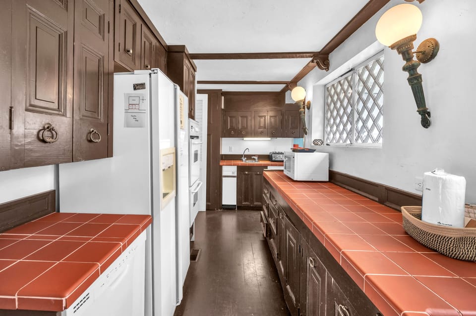 Cook your favorite meals in this charming kitchen featuring rustic wood cabinets, terracotta tile counters, and full appliances.