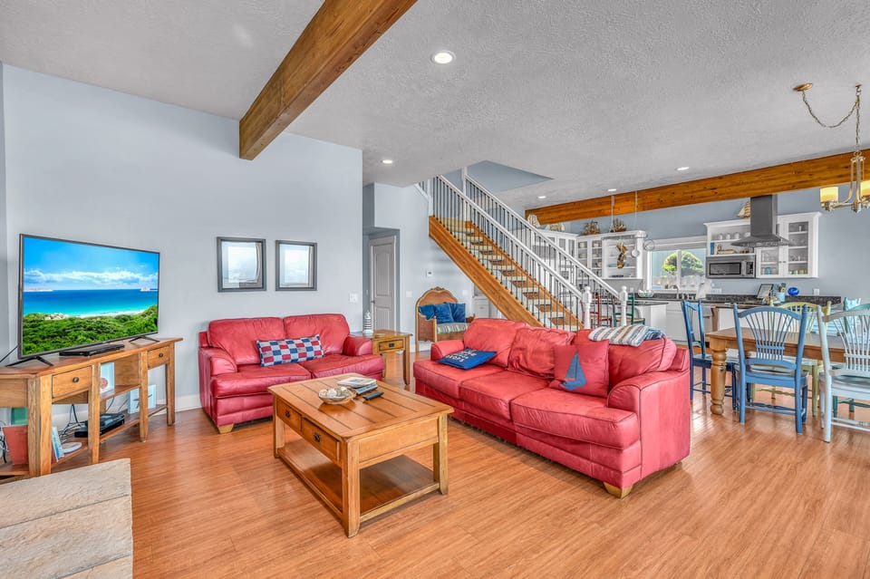 Relax in your spacious living area with exposed wooden beams, red leather seating, and open views to the kitchen.